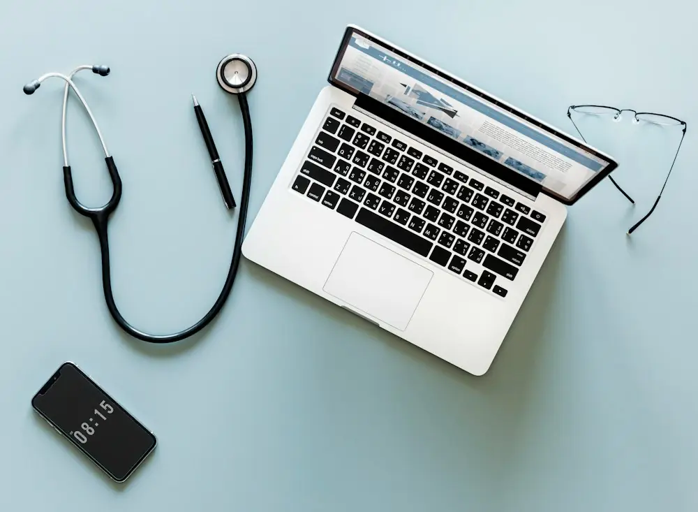 turned on MacBook in between eyeglasses and stethoscope