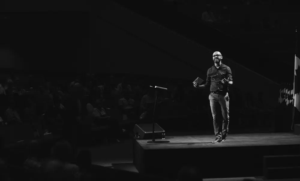 grayscale photo of man walking on platform stage